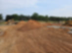 Active construction site with excavation, grading, and soil stockpiling preparing for utilities and foundations