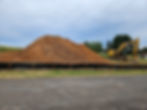 Excavator moving large dirt piles on construction site