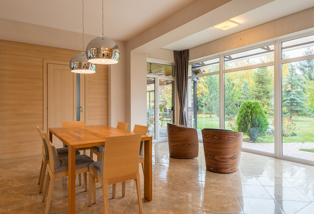 A dining room with wooden furniture and a large glass wall looking out to the garden