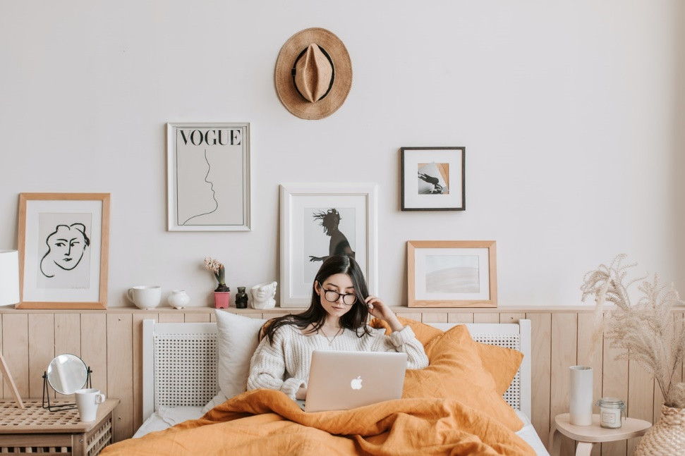 A young woman sitting in bed with her laptop