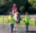 Rider on horse with one RDA volunteer leading and another sidewalking.