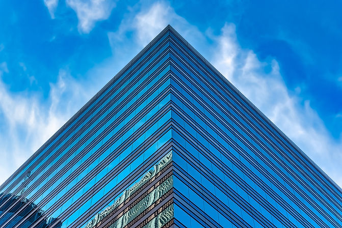 low-angle-shot-tall-glass-building-blue-cloudy-sky.jpg