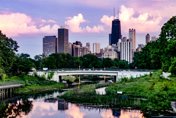 Chicago skyline reflecting off park pond with purple skies.