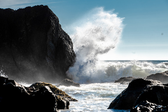 Wave crashing and splashing off rock back to ocean.