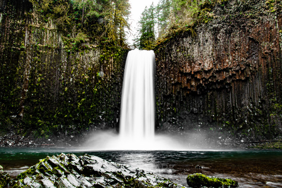 long exposure shot of waterfall surrounded by steep textured cliffs.