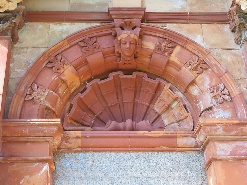 Detail of ornate red-brick arch and lion face on Brighton’s Clock Tower structure.