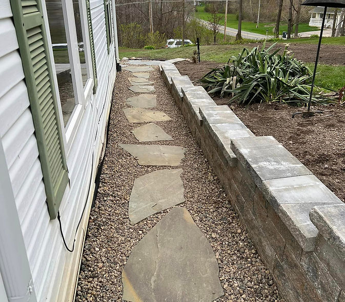 Gravel path with flagstones next to house and stone retaining wall