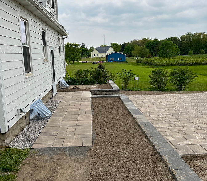 Partially installed paver patio next to a house