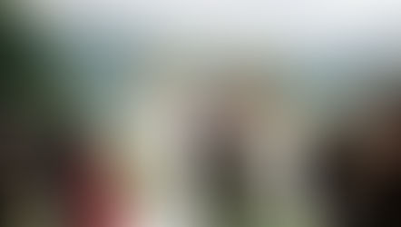 Bride and groom in traditional maori attire exchange vows under floral arch, surrounded by guests in an outdoor mountain setting.