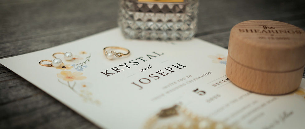 Wedding invitation for Krystal and Joseph, pearl earrings, wooden box, and a perfume bottle on a wooden surface, elegant mood.