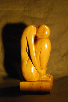 Sculpture en bois d'alisier d'une femme repliée sur elle même se tenant les chevilles.