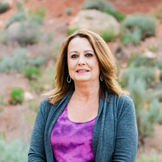 Woman outdoors in purple shirt against red rock and sage background