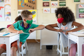 Children in school giving each other an elbow bump greeting