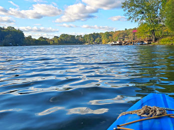 a kayak on a peaceful lake with a bright blue sky full of fluffy clouds.