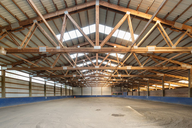 Extra large barn covered riding area with natural light and wood beams