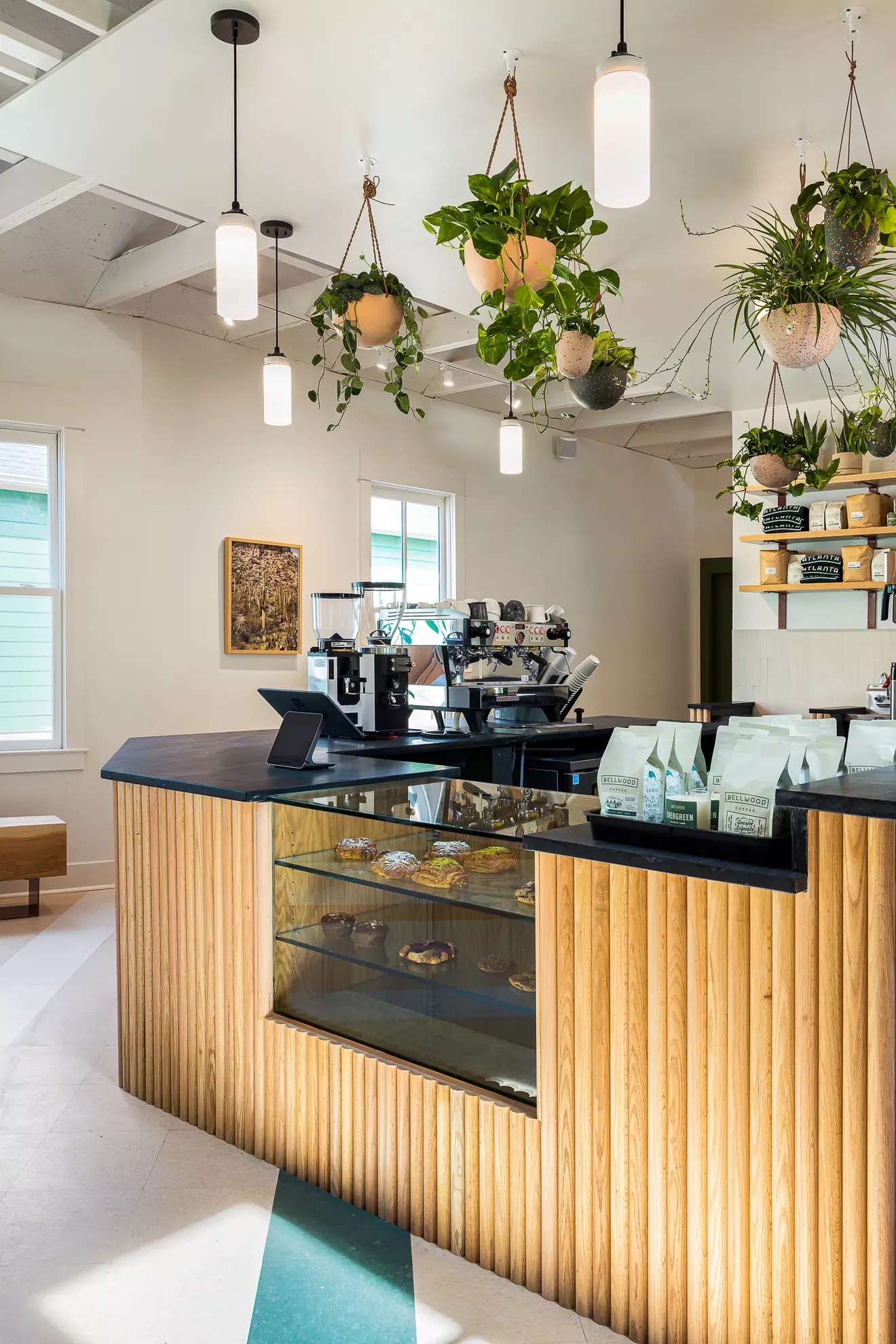 Comptoir de café en bois et marbre noir avec une vitrine en vert.