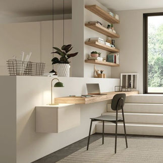 Bureau dans le salon avec une bureau en bois et une chaise noire, près d'un escalier blanc.