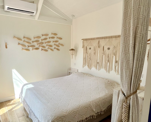 Première chambre de Lou Miou avec tête de lit en macramé, coquillages, charpente apparente et décoration bohème.