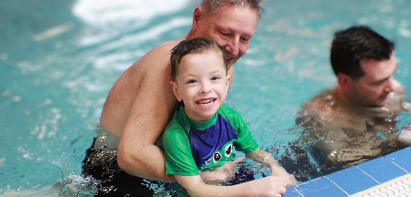 Happy boy enjoys swimming with dad