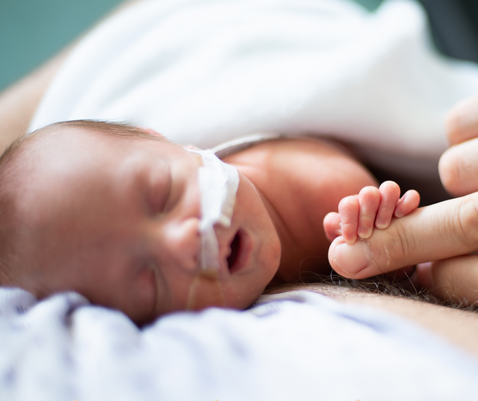 Newborn baby sleeping peacefully, parent holding tiny hand