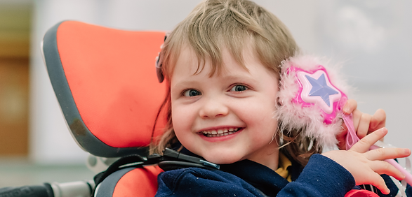 Smiling girl in wheelchair with pink star toy