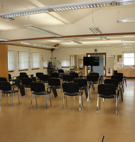 Spacious hall with chairs and screen, ideal for meetings.