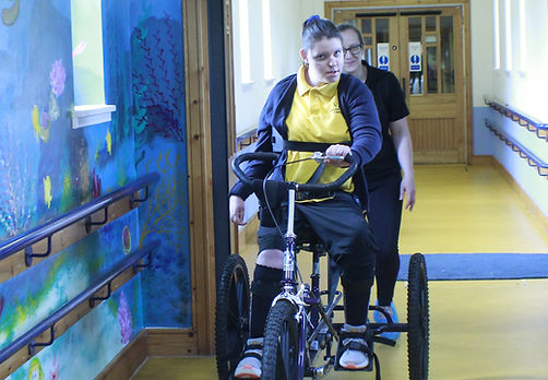 Pupil using trike to cycle through school corridors.