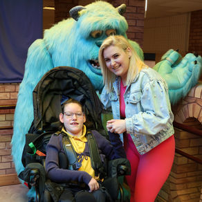 A mother and daughter smiling while holding hands beside Sully, the Craighalbert mascot.