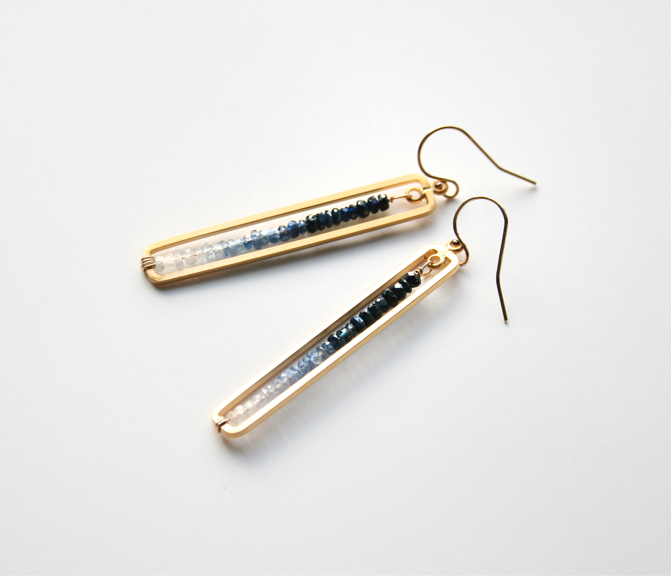 Gold rectangle frame with blue sapphire gemstones, ranging from dark blue to white.