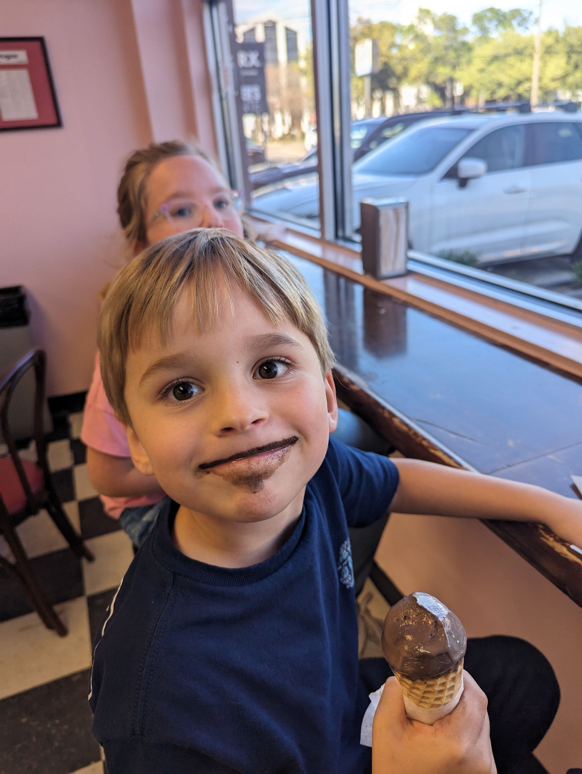 Smiling boy with chocolate on his face, holding ice cream