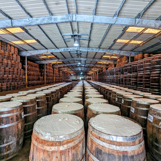 Large warehouse filled with rows of wooden barrels.