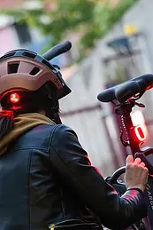 Ragazza con casco vicino alla e-bike con luce posteriore accesa