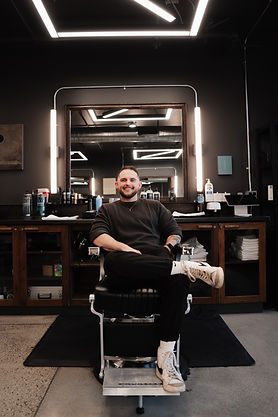 SLC Barber August sitting in chair