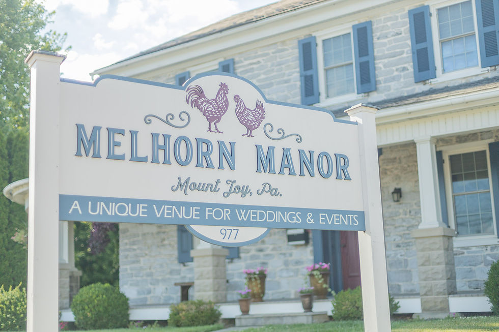 Melhorn Manor sign with rooster graphics in front of a stone house; reads Mount Joy, Pa. and venue for weddings & events.
