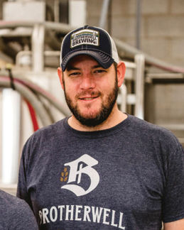 Woman leader with tattoos standing happily with arms crossed