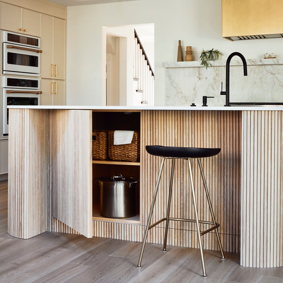 Our Wynnewood Project kitchen with a custom white oak fluted island with concealed storage. The faucet is California Faucets, the double oven is Cafe Appliances, and the stools are Rejuvenation.