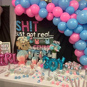 Pink and Blue balloon garland with a back drop for a gender reveal party. decorated table with pink balloon letters syaing Girl and blue balloon letters saying Boy with treats and baby items