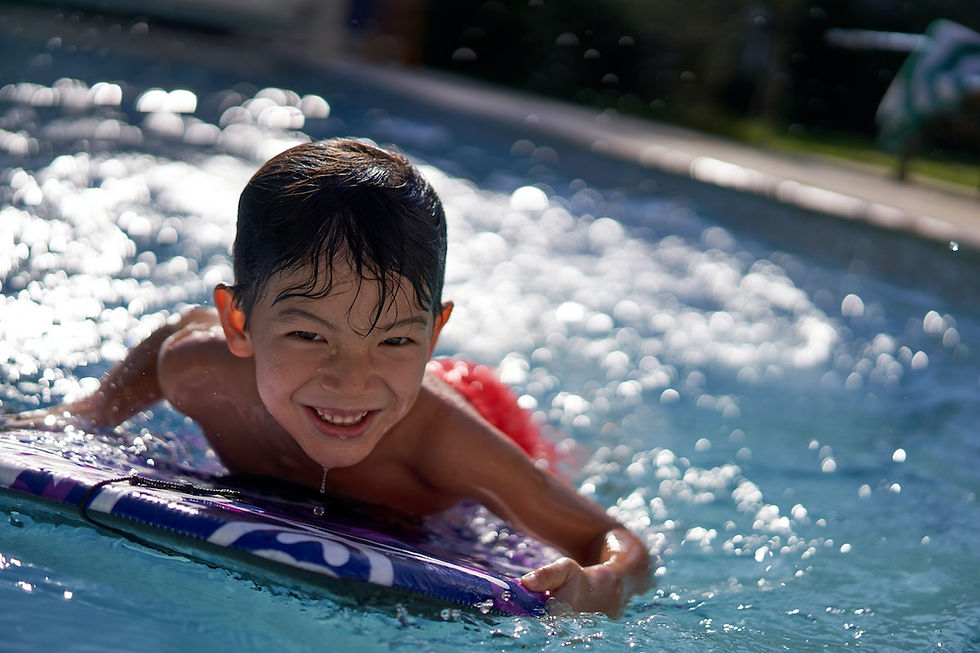Young boy riding a boogie board in the water