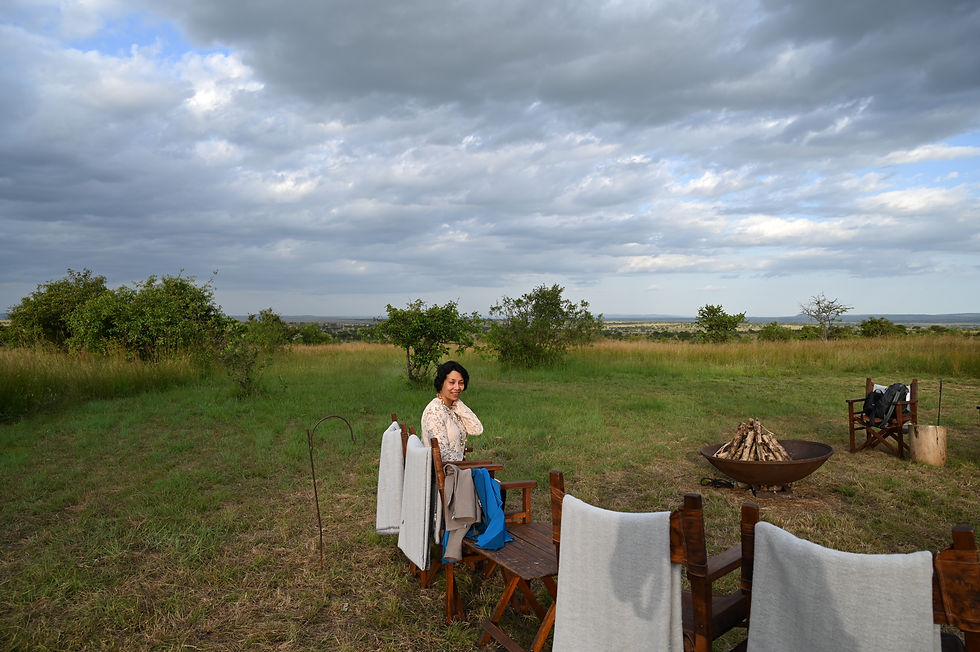 A serene moment at Kichakani Serengeti Camp, Tanzania, capturing a peaceful scene with a guest relaxing by a fire pit against the backdrop of the expansive African savannah.