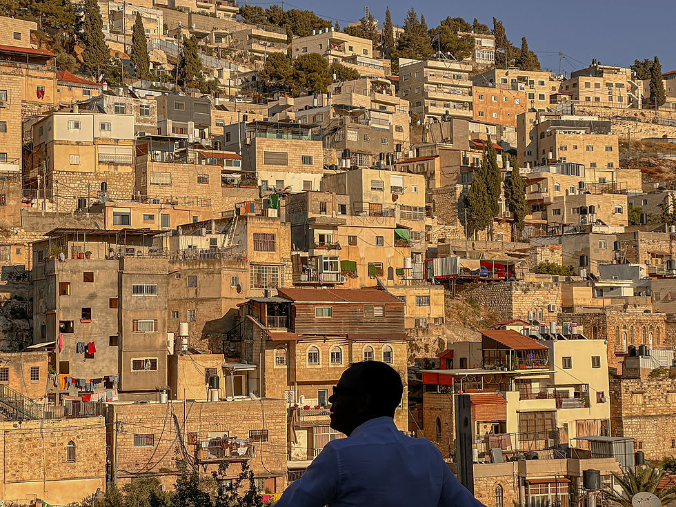 View of the densely layered buildings of East Jerusalem bathed in the warm glow of afternoon light, as seen from the Old City.
