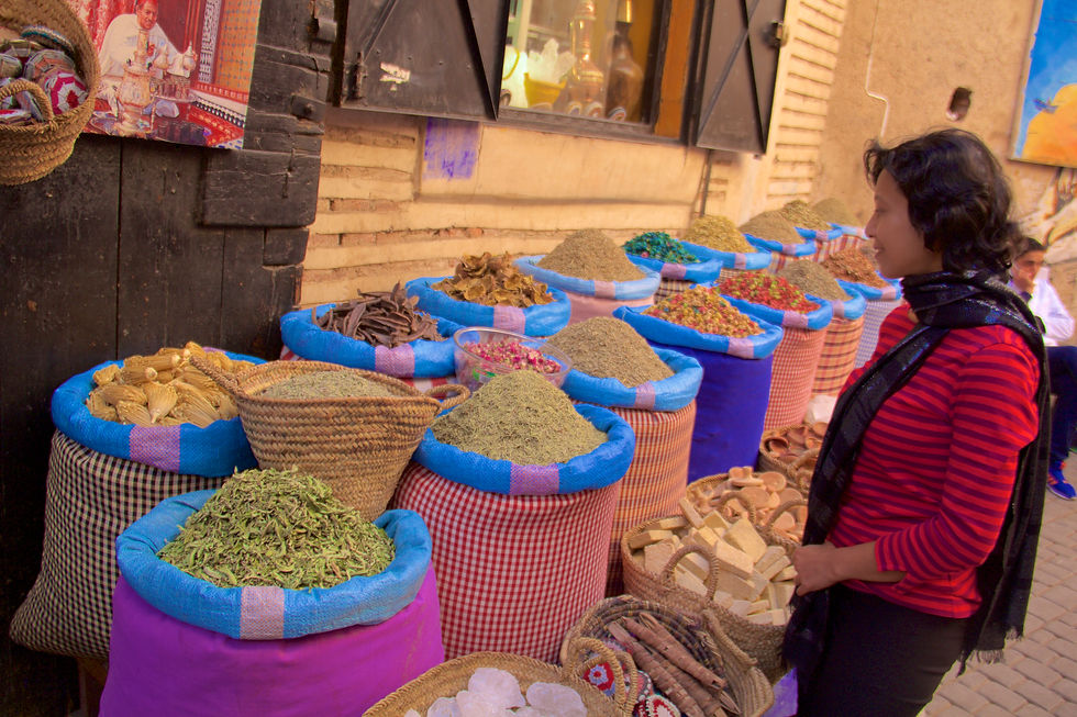 Sarmin gazes at colorful spices and herbs in Marrakesh, soaking in the vibrant ambiance of the marketplace.