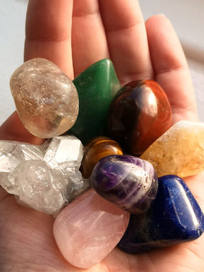 Hand holding a selection of colourful crystal tumblestones