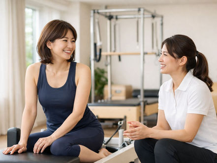西宮のパーソナルジムでマシンピラティスの指導を受ける女性とトレーナー