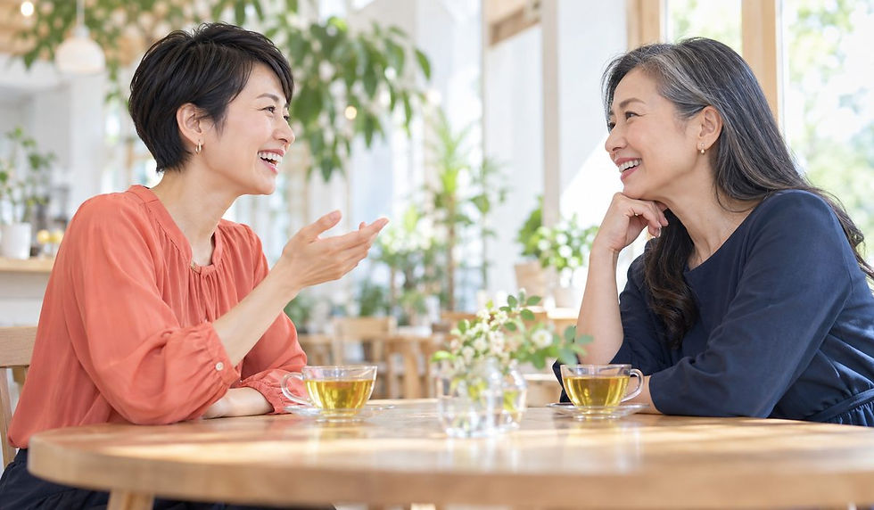 明るいカフェで、ハーブティーを前に向かい合い、笑顔で話す2人の女性