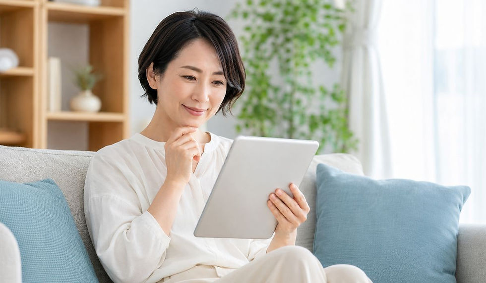 ソファに座ってタブレットを見ながらほほえむ女性