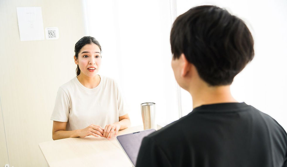 テーブル越しに男性トレーナーへ話しかける女性会員