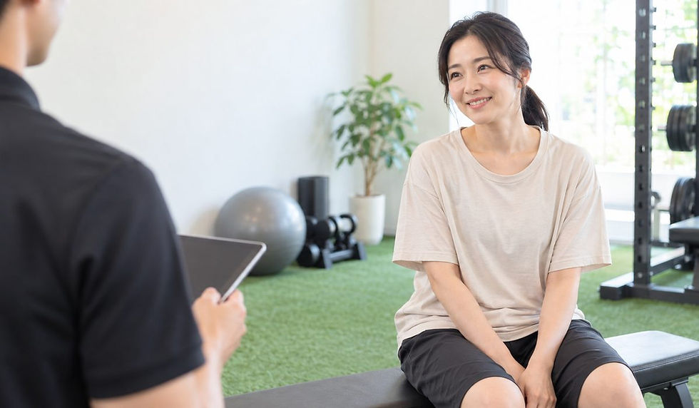 人工芝の個室でベンチに座り、トレーナーの説明を聞きながら微笑む女性