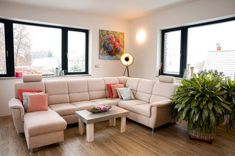 Slunný obývací pokoj s krémovou pohovkou a pokojovou rostlinou