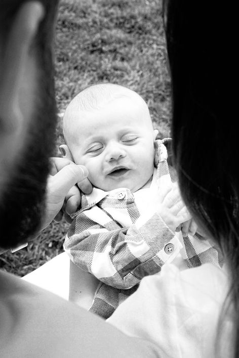 černobílá fotografie rodičů zezadu jak drží svého syna a dívají se na něj