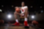 Young male basketball player sitting on court with ball, ideal for sports team photography packages